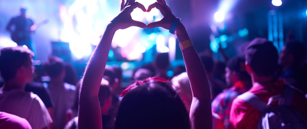 People taking photographs with smart phone during a music festival. Fans enjoying rock concert with light.